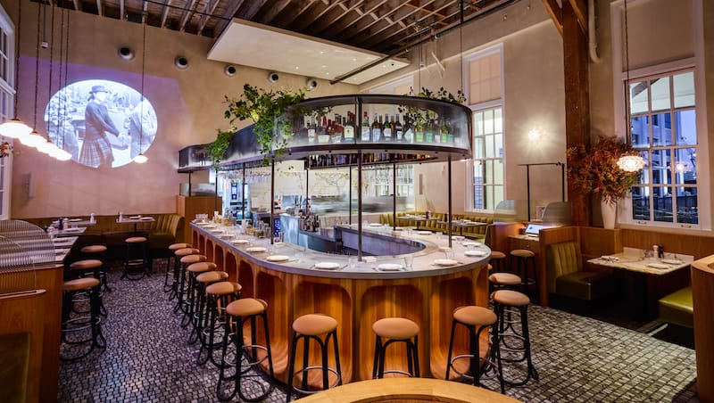 A horseshoe-shaped bar creates a focal point amid intimate banquettes in Bon Délire’s dining room. Photo: ⓒ Hardy Wilson.