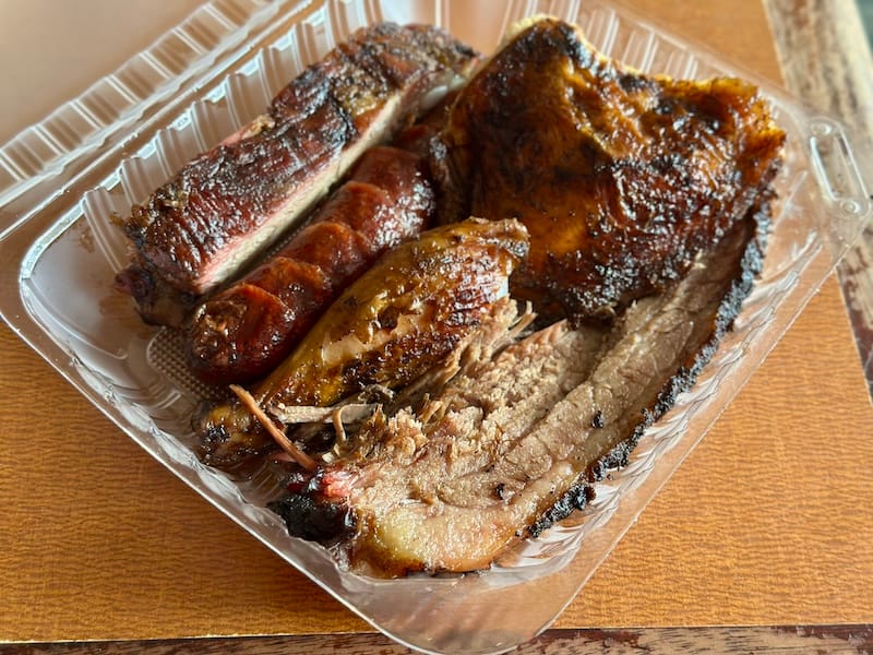 A four-way meat plate of brisket, chicken, a housemade link, and a pork rib. Photo: © tablehopper.com.