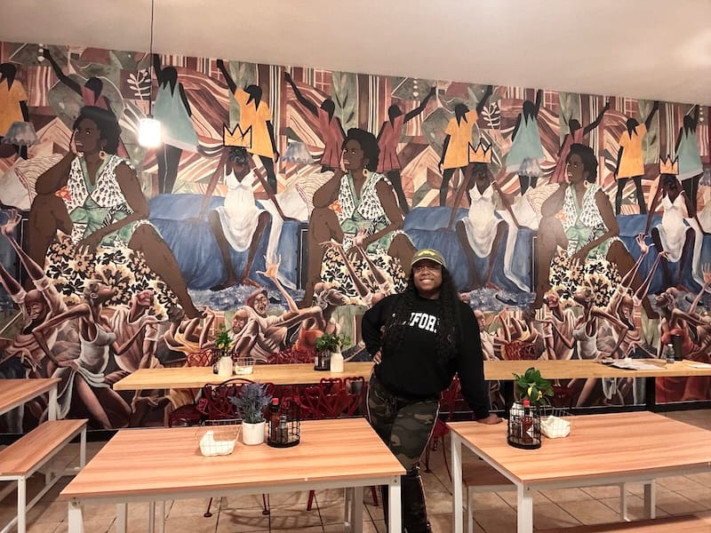 Vanessa Lee of Smoke Soul Kitchen in front of the mural she designed for her new Bayview restaurant. Photo courtesy of Vanessa Lee.